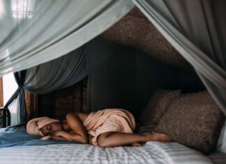 The Role of Sleep in Weight Management woman lying on bed wrapped around a towel