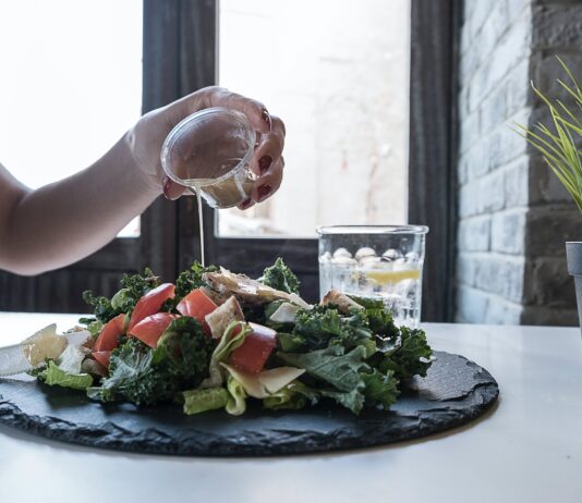 Plant-Based Diets: The Trend That’s Here to Stay person pouring dip on vegetable salad