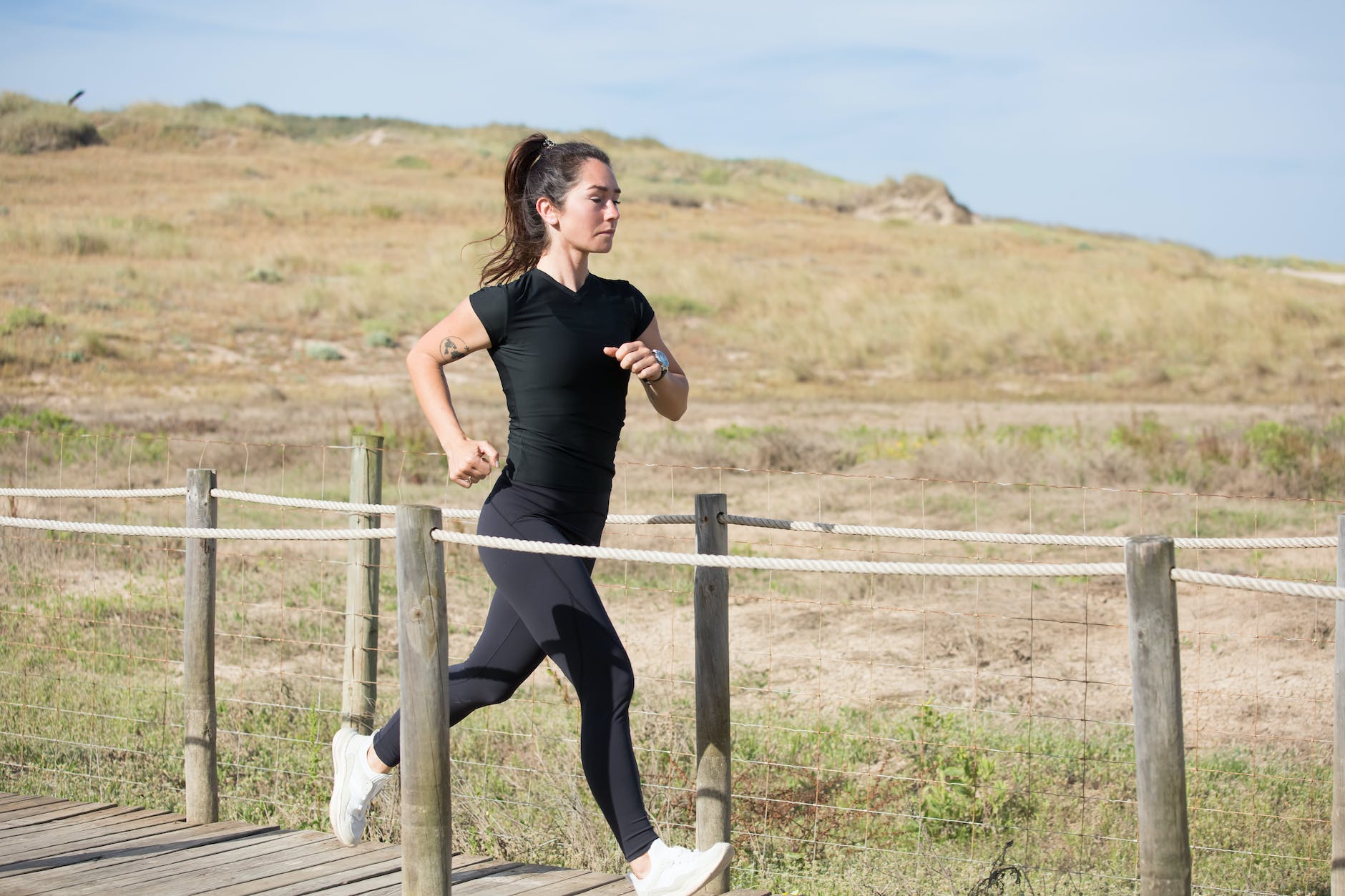 woman in black activewear running on a boardwalk