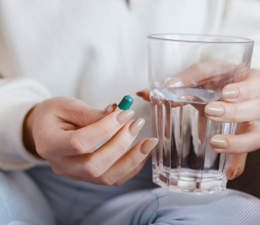 Ibuprofen Might Be Less Effective for Migraines Compared to These Three Medications woman holding pill and glass of water