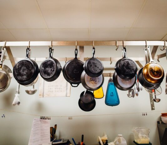Is Your Cookware Safe? Professionals Provide Insights on Ceramic, Teflon, Stainless Steel, and Glass assorted frying pans hanging on pot rack