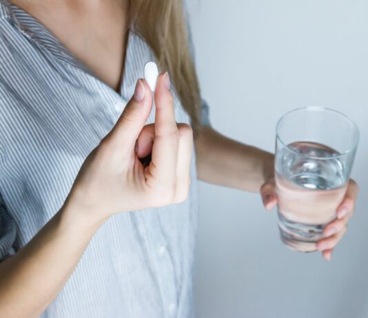 Do Digestive Enzyme Supplements Really Work? woman holding half full glass and white medicine pill