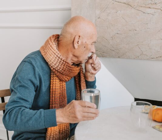 What to Do About a Cough That Won’t Go Away a man in blue long sleeve shirt holding a glass of water