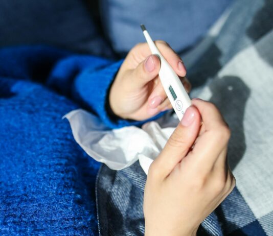 JN.1 COVID Variant Symptoms vs. Allergy Symptoms person holding thermometer