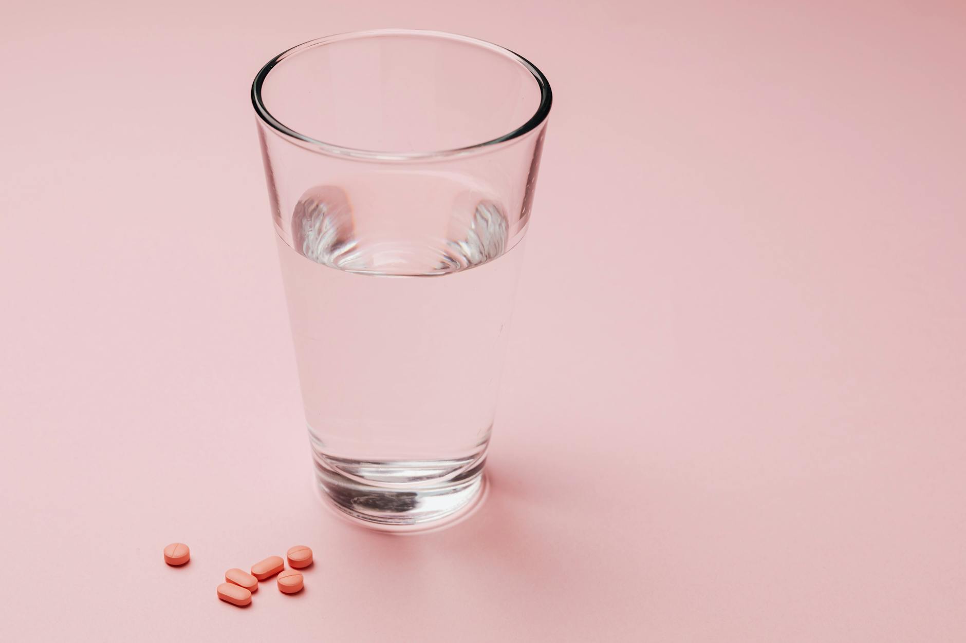 photo of glass of water beside capsules