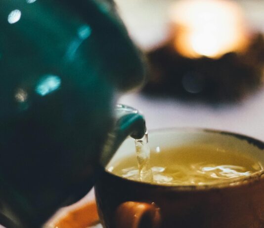 Does Green Tea Have Caffeine? person pouring liquid into brown ceramic cup